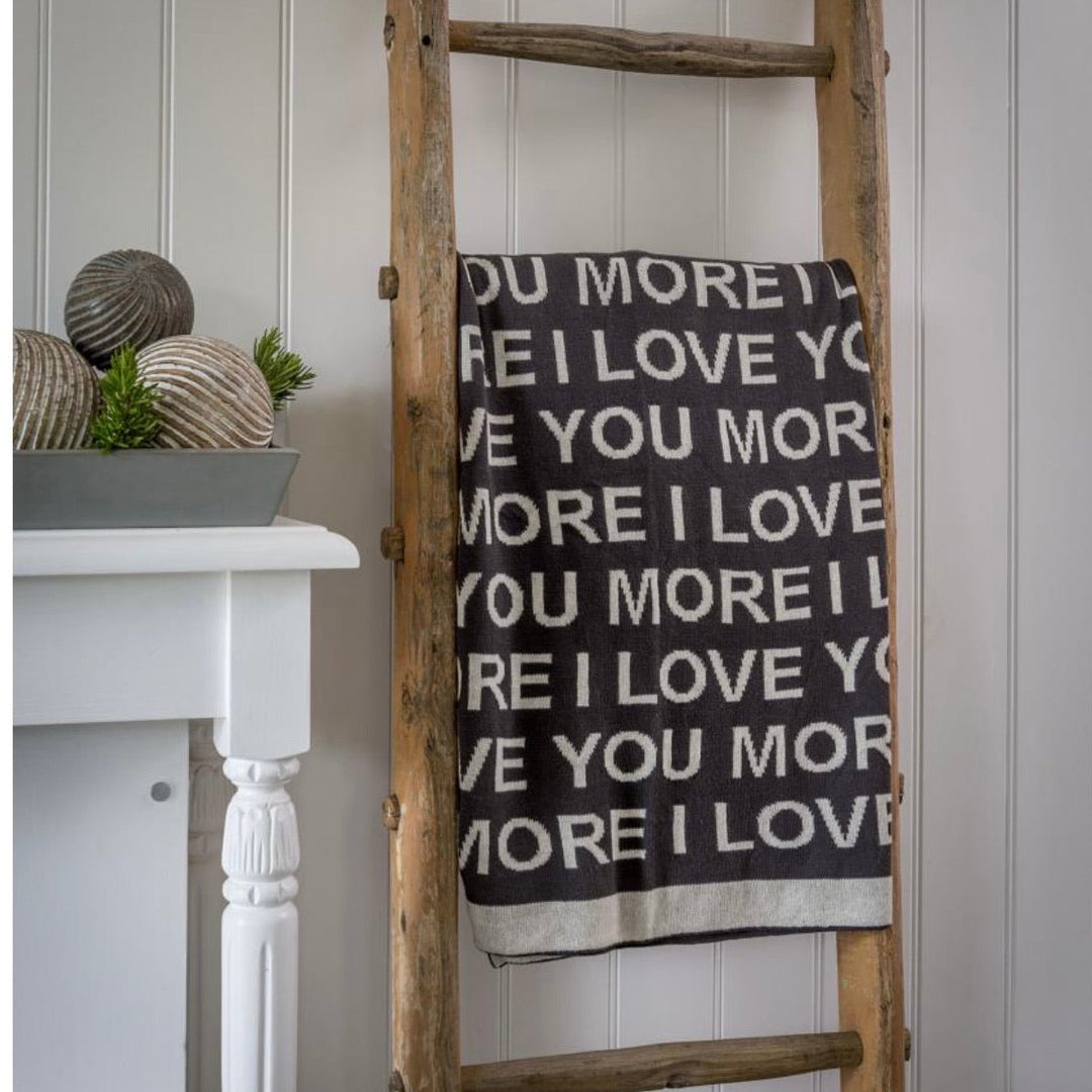 love you more knitted throw on a ladder against white wall