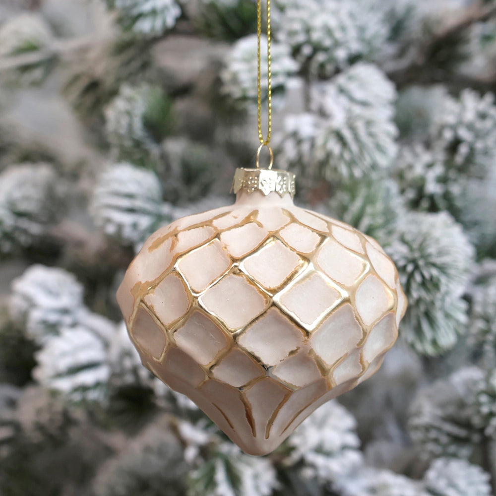 Powder pink and gold Christmas bauble on snowy fir tree