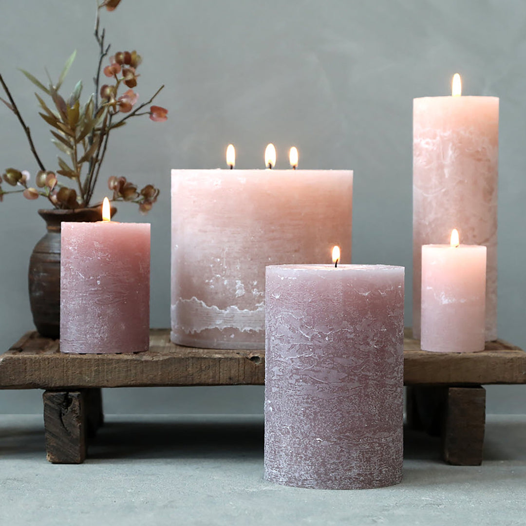 Taupe Rustic Pillar candles lit on a wooden plinth with floral arrangement