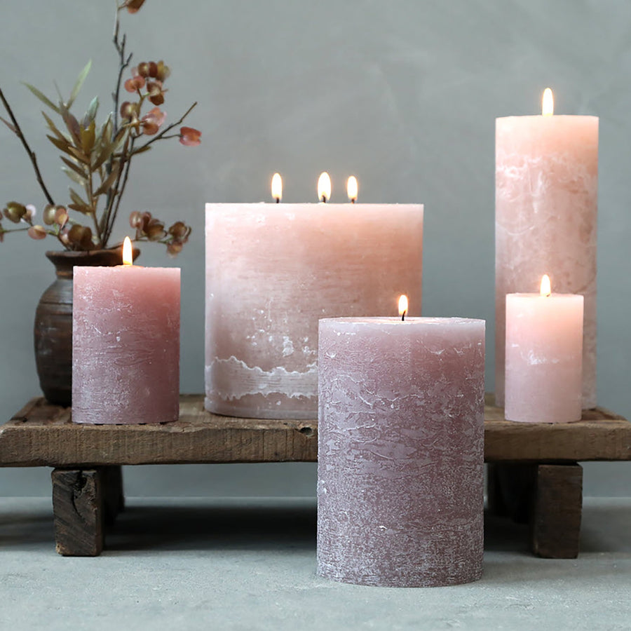 Taupe Rustic Pillar candles lit on a wooden plinth with floral arrangement