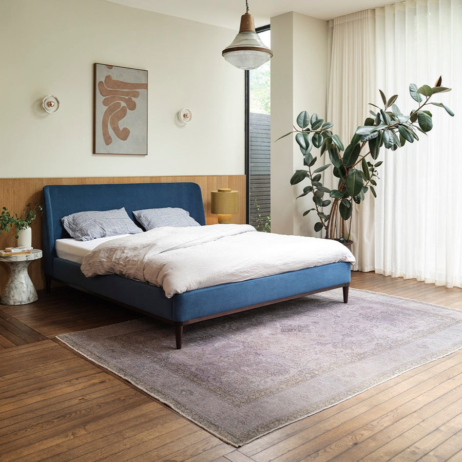 Blue velvet bed with white duvet and wooden floor